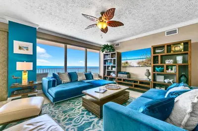 a living room with blue furniture and a view of the ocean at Hidden Dunes 503 in Panama City Beach