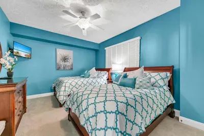 a blue bedroom with a bed and a ceiling fan at Hidden Dunes 503 in Panama City Beach