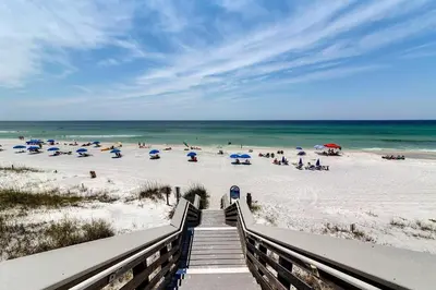 a staircase leading to a beach with people on the sand at Hidden Beach Villas 122 - A Sunset Paradise in Santa Rosa Beach