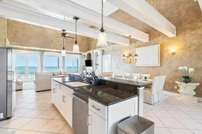a kitchen with a counter and a living room at Beachfront, 4 Bed , White Sands Haven, Penthouse ,Pool in Panama City Beach