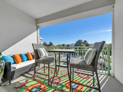 a patio with chairs and a couch on a balcony at Inn at Seacrest 309- Somewhere in the Sun in Inlet Beach