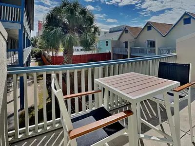 a table and chairs on a balcony with a palm tree at Sunswept Condominium #210 in Panama City Beach