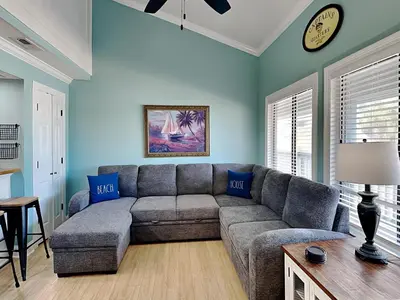 a living room with a couch and a clock on the wall at Sunswept Condominium #210 in Panama City Beach