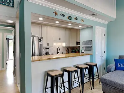 a kitchen with a bar and stools in a living room at Sunswept Condominium #210 in Panama City Beach