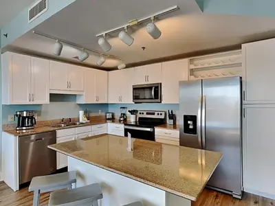 a kitchen with white cabinets and a stainless steel refrigerator at Laketown Wharf #913 in Panama City Beach
