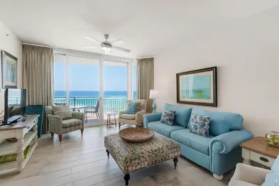 a living room with a blue couch and a view of the ocean at Aqua 0411 in Panama City Beach