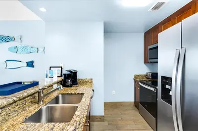 a kitchen with a sink and a refrigerator at Aqua 1904 in Panama City Beach
