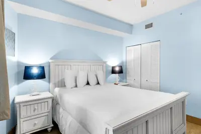 a white bedroom with a white bed and two lamps at Aqua 1904 in Panama City Beach