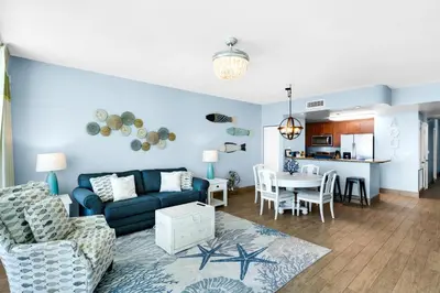 a living room with a blue couch and a table at Aqua 1904 in Panama City Beach
