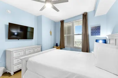 a bedroom with a white bed and a flat screen tv at Aqua 1904 in Panama City Beach