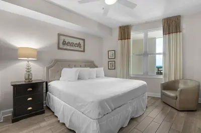 a bedroom with a bed and a chair and a window at Aqua 1905 in Panama City Beach