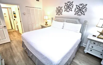 a bedroom with a large white bed and a table at Aqua 0504 in Panama City Beach