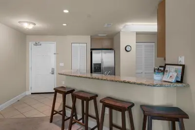 a kitchen with three bar stools and a counter at Aqua 0602 in Panama City Beach