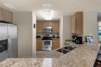 a kitchen with stainless steel appliances and wooden cabinets at Aqua 0602 in Panama City Beach