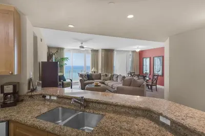 a kitchen with a sink and a living room at Aqua 0602 in Panama City Beach