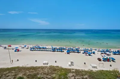 a beach with many blue and white umbrellas and the ocean at Aqua 0602 in Panama City Beach