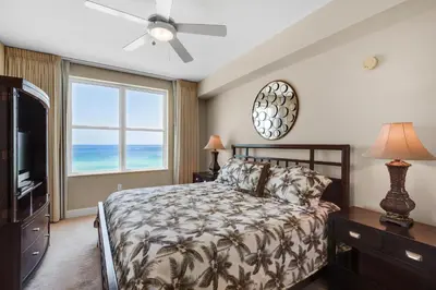 a bedroom with a bed with a ceiling fan and a window at Aqua 0602 in Panama City Beach
