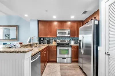 a kitchen with wooden cabinets and stainless steel appliances at Aqua 0709 in Panama City Beach