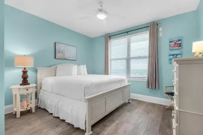 a blue bedroom with a bed and a window at Aqua 0709 in Panama City Beach