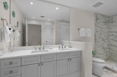 a white bathroom with two sinks and a toilet at Aqua 1802 in Panama City Beach