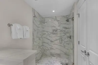 a bathroom with a shower with a stone wall at Aqua 1802 in Panama City Beach