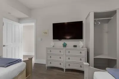 a bedroom with a white dresser with a flat screen tv at Aqua 1802 in Panama City Beach