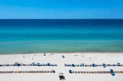 a beach with blue umbrellas and people on the beach at Aqua 1105 in Panama City Beach