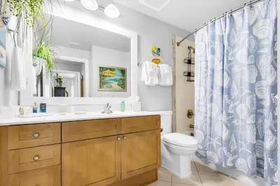 a bathroom with a toilet and a shower curtain at Aqua 1609 in Panama City Beach