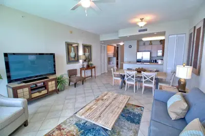 a living room with a blue couch and a tv at Aqua 2305 in Panama City Beach