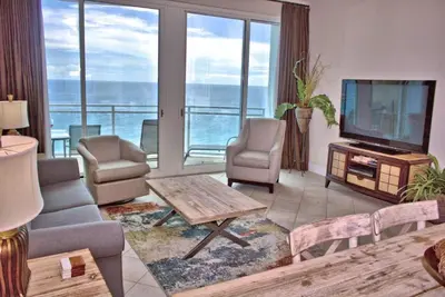 a living room with a television and a table and chairs at Aqua 2305 in Panama City Beach