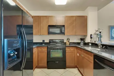 a kitchen with wooden cabinets and a black stove top oven at Aqua 2307 in Panama City Beach