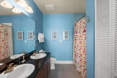 a blue bathroom with two sinks and a shower at Aqua 2307 in Panama City Beach