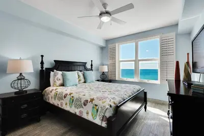 a bedroom with a bed with a ceiling fan and a window at Aqua 1402 in Panama City Beach