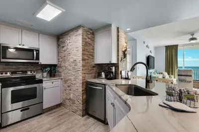 a kitchen with stainless steel appliances and a brick wall at Aqua 1402 in Panama City Beach