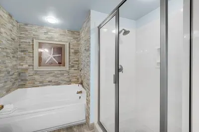 a bathroom with a shower and a white tub at Aqua 1402 in Panama City Beach