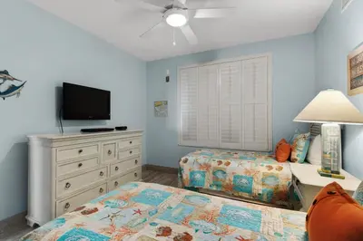 a bedroom with a bed and a tv and a dresser at Aqua 1402 in Panama City Beach