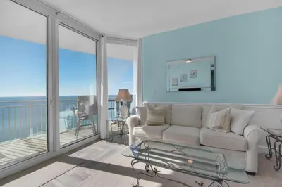 a living room with a couch and a balcony at Aqua 1711 in Panama City Beach
