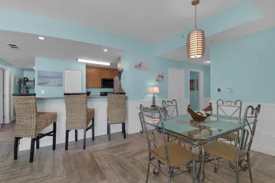 a dining room and kitchen with a glass table and chairs at Aqua 1711 in Panama City Beach