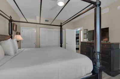 a bedroom with a bed and a dresser and a television at Aqua 1711 in Panama City Beach