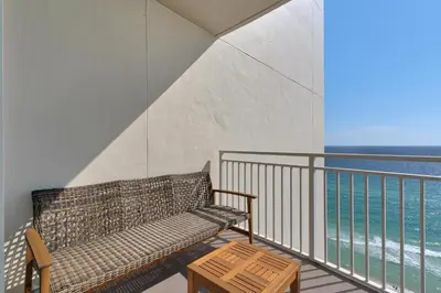 a bench on a balcony with a view of the ocean at Aqua 1711 in Panama City Beach