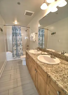 a bathroom with two sinks and a toilet and a mirror at Aqua 1502 in Panama City Beach