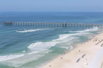 a group of people on a beach near a pier at Aqua 1502 in Panama City Beach