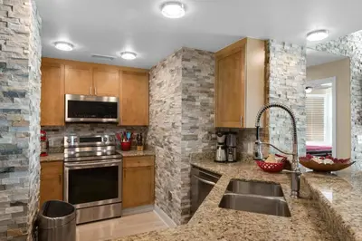 a kitchen with wooden cabinets and stainless steel appliances at Aqua 1602 in Panama City Beach