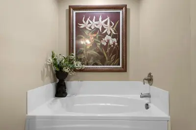 a bathroom with a white sink with a picture on the wall at Aqua 1602 in Panama City Beach
