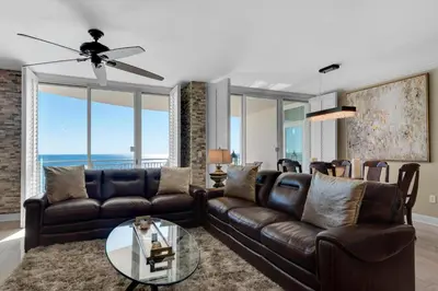 a living room with a leather couch and a glass table at Aqua 1602 in Panama City Beach