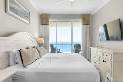 a white bedroom with a bed and a view of the ocean at Aqua 2308 in Panama City Beach