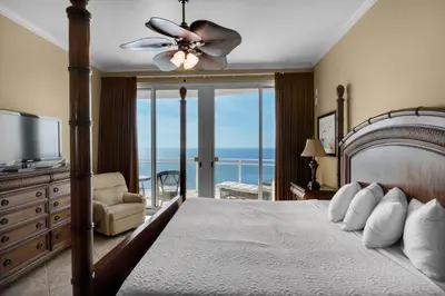 a bedroom with a bed with a ceiling fan and a balcony at Aqua 2201 in Panama City Beach
