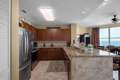 a kitchen with wooden cabinets and a stainless steel refrigerator at Aqua 2201 in Panama City Beach