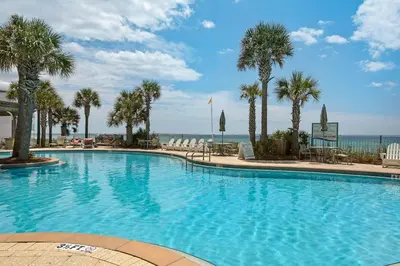 a large swimming pool with palm trees and the ocean at Aqua 2201 in Panama City Beach