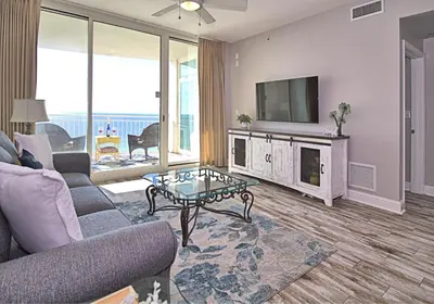 a living room with a couch and a tv and a table at Aqua 1507 in Panama City Beach